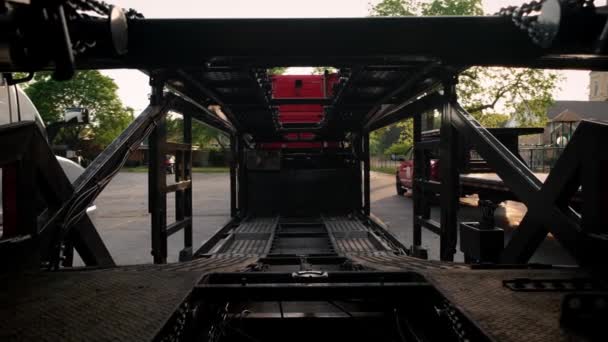 Camiones con un transportista de coches de pie en el estacionamiento. Vista trasera — Vídeos de Stock