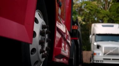 Otoparkta duran bir araba taşıyıcısı olan kamyonların lastiklerinin görüntüsünü kapat. Arka plan, kamerayı oynat