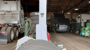 Kamyon tamirhanesi. Kamera atölyede durduğu raya gider ve onarımları bekler. Arka Geniş açı