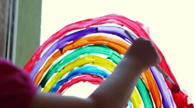 Close up of Painting rainbow at home window. Stay at home Social media campaign for coronavirus prevention, on sunny day