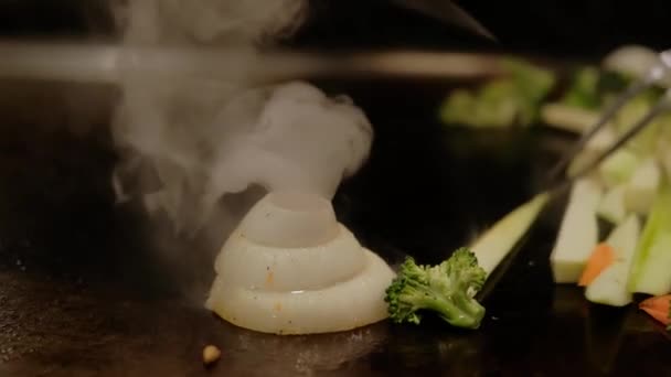 Nahaufnahme des japanischen Chefkochs beim Kochen von Teppanyaki auf Hibachi mit Meeresfrüchten-Garnelen und Jakobsmuscheln, die auf einer heißen Platte gebraten werden. Zeitlupe — Stockvideo