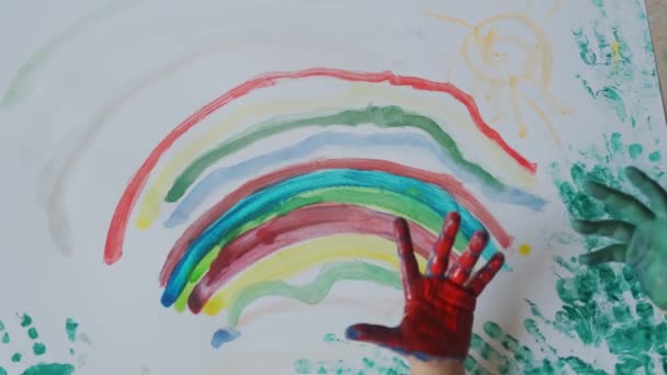 Mała dziewczynka z farbami na rękach rysuje na białym papierze. Widok z góry. Zwolniony ruch — Wideo stockowe