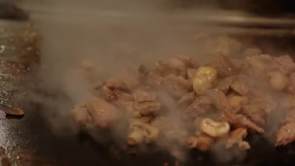 Aus nächster Nähe. Japanischer Koch kocht Teppanyaki auf Hibachi mit Meeresfrüchten-Garnelen und Jakobsmuscheln, die auf heißen Tellern gebraten werden. Zeitlupe — Stockvideo