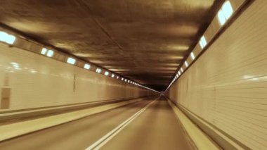 Araç ya da kamyon görüntüsü tünelden geçiyor. Sıcak sarı ışık. 