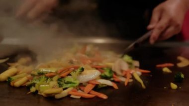 Japon şef teppanyaki pişiriyor. Elektrikli ocakta kızartılmış. Yavaş çekim. Yakın çekim.