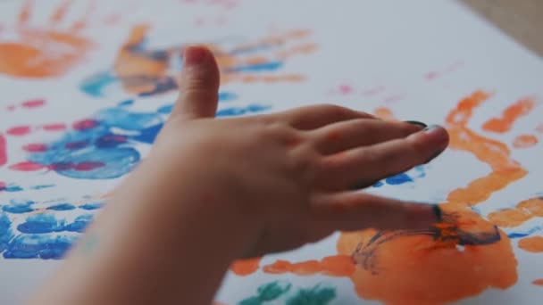 La bambina con le vernici sulle mani attinge alla carta bianca. Vista dall'alto. Close up Colpo al rallentatore — Video Stock