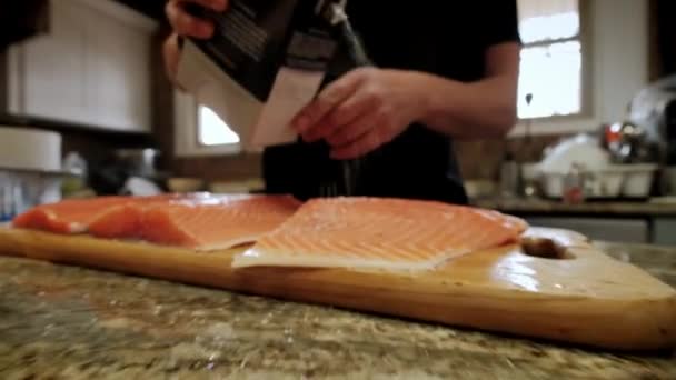 Vaří ruce nakládaný losos filet kousky v profesionální dřevěné kuchyňské desce — Stock video