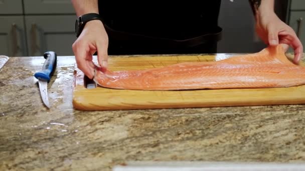 Mãos de cozinheiros corta o peixe em pedaços para processamento posterior. Mova a câmera — Vídeo de Stock