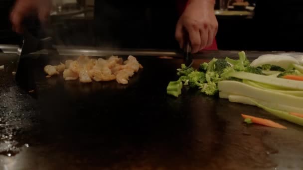 Primer plano. Chef japonés cocinando teppanyaki en hibachi con camarones de mariscos y vieiras fritas en plato caliente. Movimiento lento — Vídeo de stock