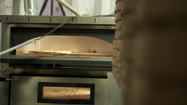 Pizzayı bir restoranın elektrikli fırınına koyarken yakın çekim görüntüsü, — Stok video