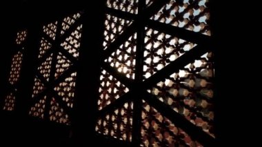 Güneş, oyulmuş pencere gölgelerinin arasından parlıyor.