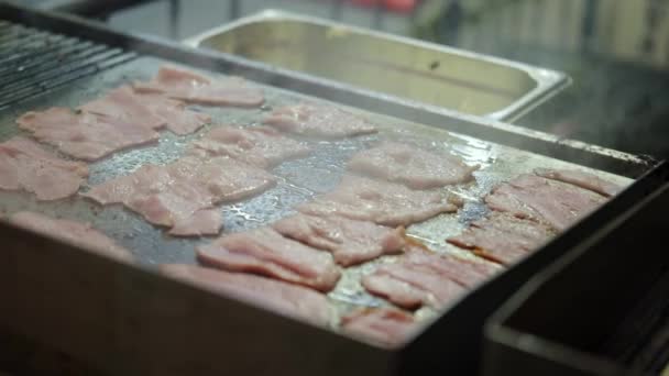 Usmažte kousky slaniny na pánvi. Křupavé kousky lahodné slaniny se smaží v pánvi. Pásky slaniny, smažené na pánvi. Široký záběr — Stock video