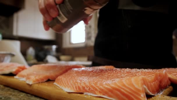 Fecha. Cozinheiros mãos picles pedaços de filé de salmão em uma placa de cozinha de madeira profissional — Vídeo de Stock