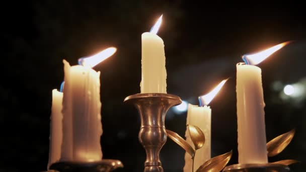 Candles in a metal candlestick burn at night on a black background Five burning candles in a candlestick. Close up — Stock Video