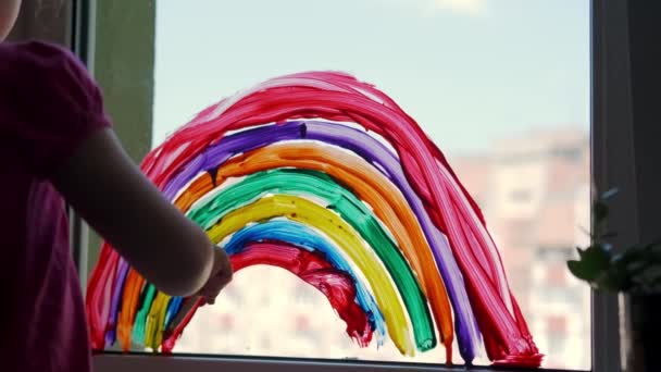 Pintando arco iris en la ventana de casa. Quédese en casa Campaña de medios sociales para la prevención del coronavirus, en un día soleado — Vídeo de stock
