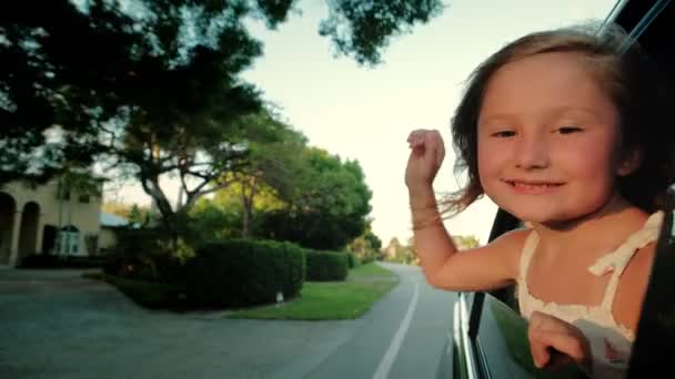 Tiener meisje dat uit het raam gluurt en met zijn hand zwaait. Familie reizen met de auto. Langzame beweging. Close-up fusie — Stockvideo