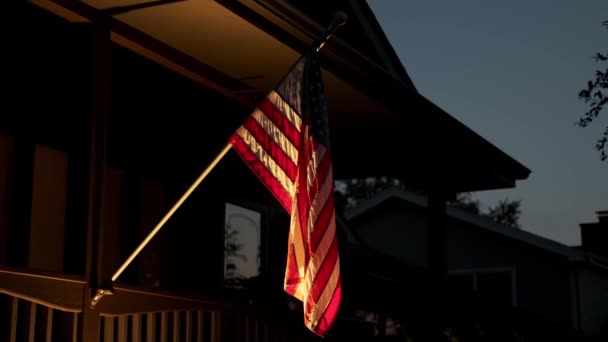 De Amerikaanse vlag is bevestigd aan een privé-huis en 's nachts verlicht door licht — Stockvideo