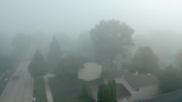 Weitwinkel-Drohnenaufnahme einer Wohngegend, die während eines lebendigen Sonnenaufgangs von Nebel bedeckt ist. — Stockvideo
