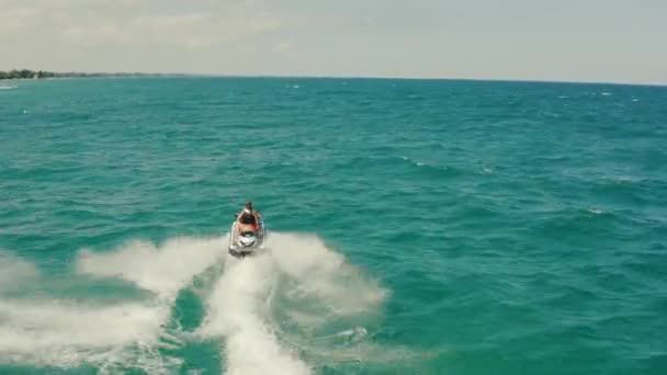 Drone aérien suite à la prise de vue d'un couple sur un jet de ski traversant des vagues. Météo pour Sunny and Ocean Vue de dos — Video