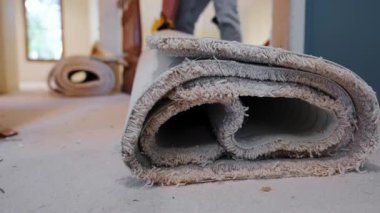 Carpenter lifting up the roll of old carpet during home repair. Close up view. . High quality 4k footage