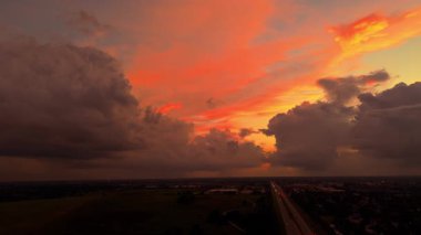 Gün batımında trafik karayolu ve banliyö üzerinde altın katmanlı bulutlarla dolu renkli dramatik bir gökyüzü. Yüksek kalite 4k görüntü