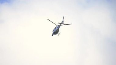 Naperville lL 'de. ABD 22 sep 2025. Haber helikopteri havada süzülüyor, ana pervanesi onu havada sabit tutacak kadar kaldırma gücü üretiyor. Bulutlu gökyüzüne karşı aşağıdan görüntü. Ağır çekim. Yüksek kalite 4k görüntü