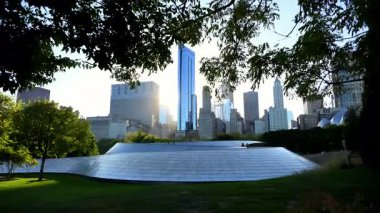 Chicago şehir merkezindeki modern yüksek binalar ve altın gün batımıyla modern BP Köprüsü manzaralı. Chicago manzarası güneş ışığına karşı. Yüksek kalite 4k görüntü