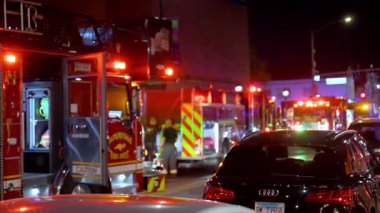 Sokağa park etmiş el fenerli itfaiye araçları ve küçük bir kasabanın merkezinde çalışan itfaiyecilerin silueti bulanıklaştı. USA IL Naperville 5 Ekim 2025. Yüksek kalite 4k görüntü