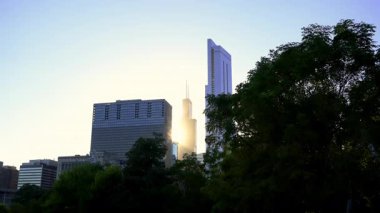 Willis Kulesi ve Chicago 'daki gökdelenler batan ya da doğan güneşin sıcacık ışığıyla aydınlatılıyor. Gökdelenler arasındaki güneş ışığı akıntıları, berrak bir gökyüzüne karşı siluet oluşturur. Yüksek kalite 4k görüntü