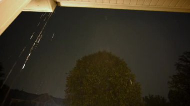 Fırtınada çatıdan düşen gökyüzüne ve yağmur suyuna bakıyorum. Gökyüzünde şimşek çakan şimşek. Binanın içinden yakın çekim. Yüksek kalite 4k görüntü