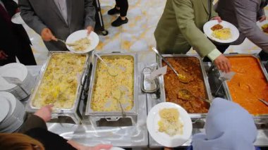 Konukların Hint ya da Pakistan büfe yemeklerinin keyfini çıkarırken yakın plan çekimleri. Etkinlikte çeşitli rengarenk yemekler olacak. Manzaranın üstünde. Yüksek kalite 4k görüntü