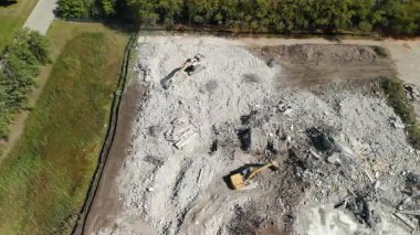 Yıkım alanı, kazıcıların geniş enkaz ve kir alanı üzerinde çalıştığı. Zemin molozlarla kaplı, beton veya eski yapının kalıntıları yıkılıyor. Ağır çekim. Yüksek kalite 4k görüntü