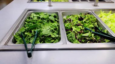 Markette yenmeye hazır yeşil salatalı ıspanak çeşitleri raflardaki tepsilerde düzgünce sergileniyor. Kapatın. Yüksek kalite 4k görüntü