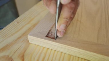 Ahşap parçasına yontulmuş bir keskiyle ahşap işçisi. Zanaatkar, tenha eklem bölgesini temizlemek ve şekillendirmek için dikkatli ve kontrollü el hareketleri kullanır. Yüksek kalite 4k görüntü