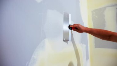 İnşaat işçisi, metal bir bantlama bıçağıyla alçıpan köşesine eklem bileşimi yayıyor. Duvar düzleştirildi ve bir ev tadilatının parçası olarak tamamlandı. Yüksek kalite 4k görüntü