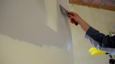 İnşaat işçisi metal bir bant bıçağıyla duvarlara eklem bileşimi yayıyor. Duvar, tadilat ya da tadilat projesinin bir parçası olarak düzeltildi ve tamamlandı. Yüksek kalite 4k görüntü