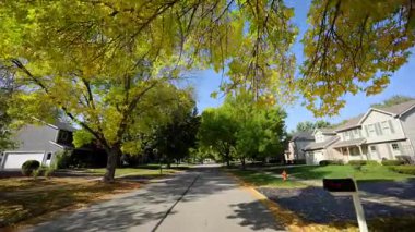 Güneşli bir sonbahar mahallesinde küçük kasaba sokaklarında araba sürerken görüntüsü. Yüksek kalite 4k görüntü