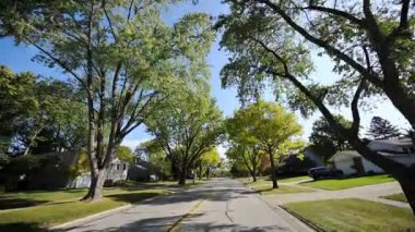 Güneşli bir sonbahar mahallesinde küçük kasaba sokaklarında araba sürerken görüntüsü. Yüksek kalite 4k görüntü