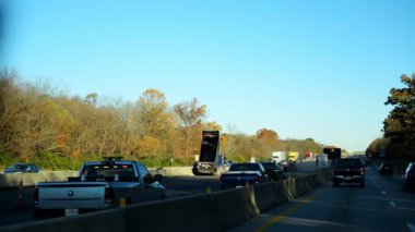 Hebron IN. ABD, 10 Eylül 2025. Sonbaharda inşaat sahasının yakınındaki bir otoyolda araba sürme olayı. Arabalar her iki tarafta da sonbahar yaprakları olarak yol boyunca seyahat ederler. Yüksek kalite 4k görüntü
