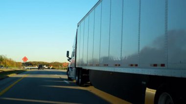 Açık bir sonbahar gününde yoğun bir otoyol boyunca kargo taşıyan yarı kamyon. Karavan sürekli trafikte, uzun mesafeli taşımacılık, lojistik ve tedarik zinciri operasyonlarında hareket ediyor. Yüksek kalite 4k görüntü