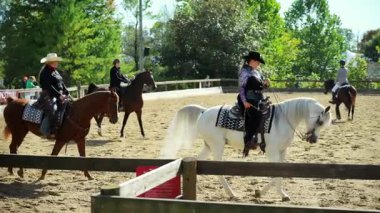 Binicilik performans takımı kumlu bir arenada ata biniyor. Sürücüler senkronize bir düzende çalışıyorlar. USA IL Warrenville 2 Ekim 2025. Yüksek kalite 4k görüntü