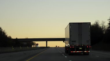 Yarı kamyonlar 15 metrelik yarı karavanla Golden Sunset Köprüsü 'nün altındaki bir otoyolda ilerliyorlar. Amerika eyaletleri arası uzun mesafe nakliye aracı. Yüksek kalite 4k görüntü