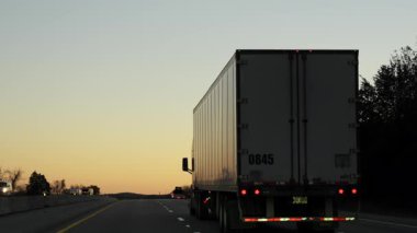 Yarı kamyonet, 25 metre kuru karavanla altın gün batımına doğru bir otoyolda ilerliyor. Amerika eyaletleri arası uzun mesafe nakliye aracı. Yüksek kalite 4k görüntü