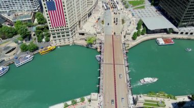 Burası Chicago şehir merkezi, Wrigley binasında büyük ABD bayrağı, caddelerde trafik ve Chicago nehri ve nehir yürüyüş alanı. USA IL Chicago 20 Haziran 2025. Yüksek kalite 4k görüntü