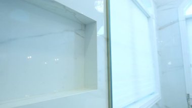 Mermer duş boşluğunda ve bitişikteki banyoda cam duvarda inşa edilmiş. Ev tadilatı, banyo tasarımı, gayrimenkul, modern yaşam, iç dekorasyon ve lüks ev özellikleri. Yüksek kalite 4k görüntü