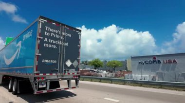 Amazon Prime yarı kamyoneti gün ışığında yoğun bir otoyolda seyahat ediyor. Amazon markalı mavi römork parlak bir gökyüzü altında trafiğin içinden geçiyor. Miami FL 'de. ABD, 10 Nisan 2025. Yüksek kalite 4k görüntü