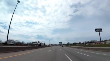 Gündüz vakti otoyolda araba kullanmak. Beyaz bulutlar parlak bir mavi gökyüzünde sürükleniyor. POV görünümü. Zaman ayarlı. ABD KY Louisville 28 Mart 2025. Yüksek kalite 4k görüntü
