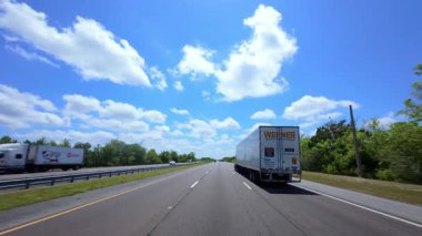 Açık güneşli bir günde, yarı kamyon otoyol boyunca kargo taşır. Araç sürekli, uzun mesafeli taşımacılık ve lojistikte hareket ediyor. POV görünümü. ABD FL Miami 02 Nisan 2025. Yüksek kalite 4k görüntü