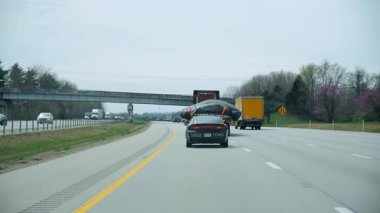 Bir üst geçidin altında otobanda devriye ya da eskort aracıyla seyahat eden büyük bir yük kamyonu. Gündüz vakti büyük kargo taşımacılığı. ABD Elizabethtown KY 25 Mar 2025. Yüksek kalite 4k görüntü