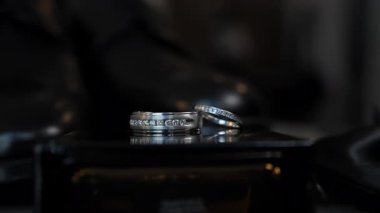 Çift nikah ve nişan yüzükleri manzarayı kapatır. Hazırlık anları. Gelinin sabahı. Aydınlatılmış halkalar. Yüksek kalite 4k görüntü